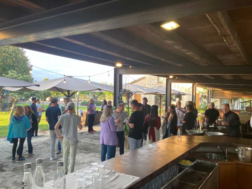 AQai team members and event attendees networking outdoors under a covered patio, using conference planning tools to coordinate social activities at an AQai retreat.