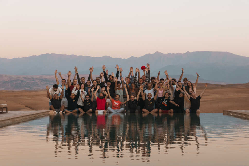 Giant swarm team posing in the background against a beautiful mountain backdrop and a pool.